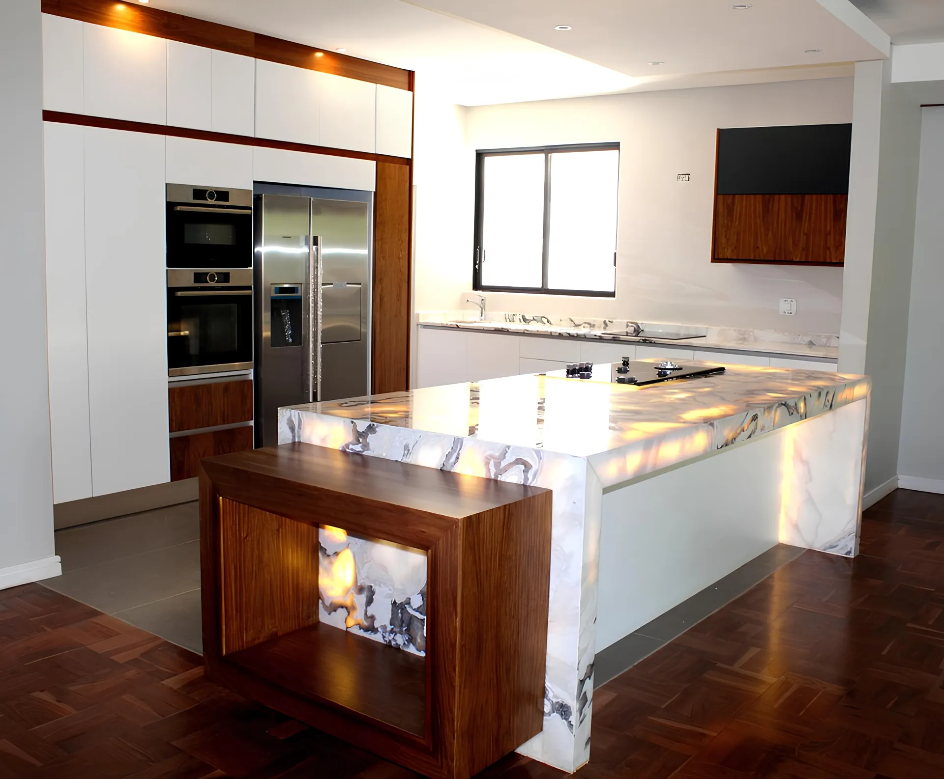 Kitchen with a backlit onyx waterfall island and walnut cabinetry trim, fitted by N.D.I.